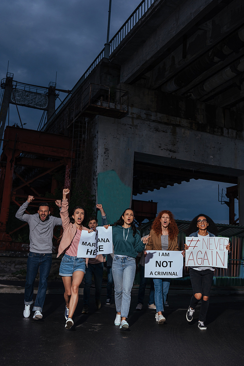 emotional group of multicultural people holding placards in evening