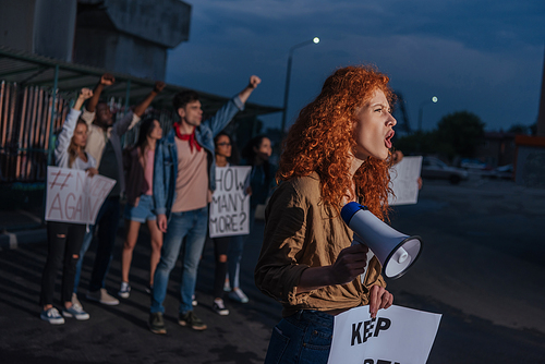 selective focus of curly redhead girl holding placard and screaming on meeting