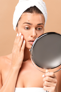 selective focus of young woman with pimple on face looking at mirror isolated on beige