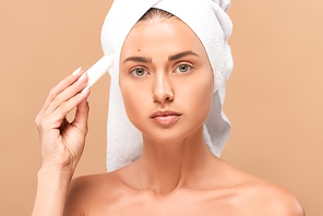naked girl in towel holding treatment cream near face with problem skin isolated on beige