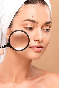 young nude woman with pimples on face holding magnifier isolated on beige