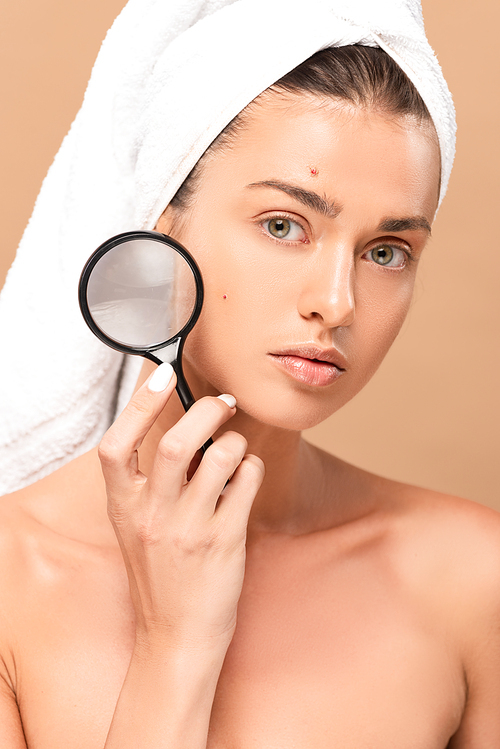 nude woman with pimples on face holding magnifier isolated on beige