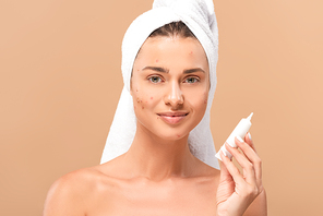 happy and naked girl with acne on face holding treatment cream isolated on beige