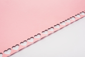 pink paper with cut out hearts on white background
