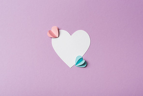 top view of blank card with colorful paper hearts on violet background