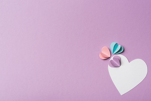 top view of blank card with colorful paper hearts on violet background