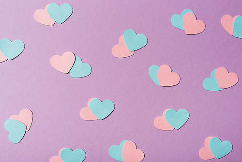 seamless pattern of colorful paper hearts on violet background