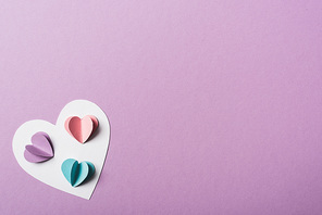 top view of colorful paper hearts on white card on violet background