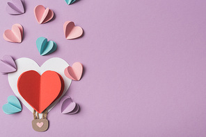 top view of colorful paper hearts around heart shaped paper air balloon on violet background