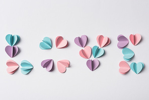 top view of love lettering made of colorful paper hearts on white background