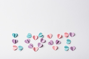 top view of love lettering made of colorful paper hearts on white background