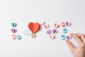 top view of love lettering made of colorful paper hearts and air balloon with clouds on white background