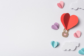 top view of colorful paper hearts and air balloon with clouds on white background