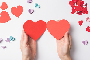 partial view of woman holding blank red heart shaped hearts on white background
