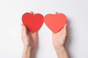 partial view of woman holding blank red heart shaped hearts on white background