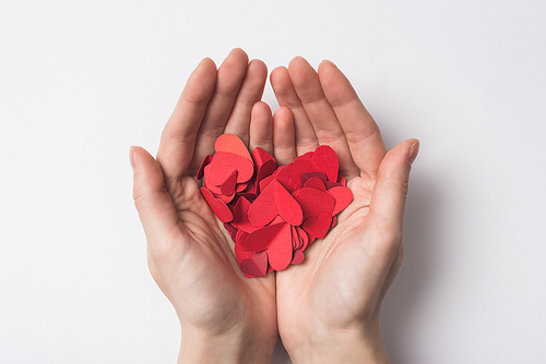 partial view of woman holding paper red hearts on white background