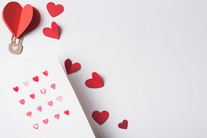 top view of valentines greeting card and paper red hearts on white background