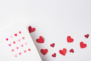 top view of valentines greeting card and paper red hearts on white background