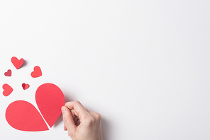 cropped view of woman holding red broken heart pieces on white background