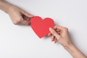 cropped view of women holding red heart on white background