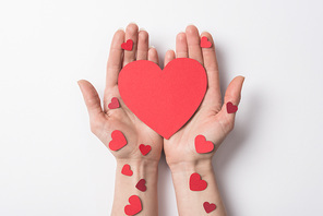 cropped view of woman holding red hearts on white background
