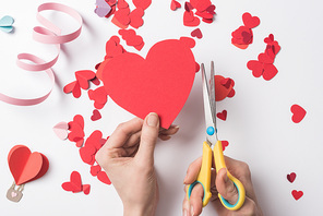 cropped view of woman holding red heart and scissors on white background