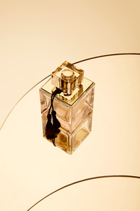 High angle view of perfume bottle on round beige mirror surface