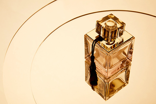 High angle view of aromatic perfume bottle on round mirror surface with reflection