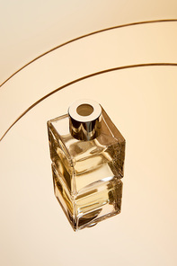 High angle view of perfume bottle on round beige mirror surface with reflection
