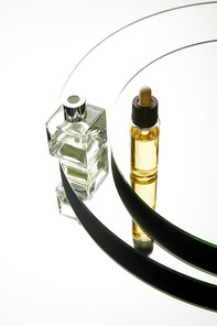 High angle view of luxury perfume bottle and serum bottle on mirror surface