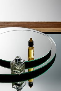 High angle view of perfume bottle and serum bottle with oil on mirror surface