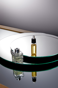 High angle view of perfume bottle and serum bottle on mirror surface
