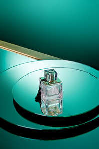 High angle view of purple perfume bottle on green round mirror surface