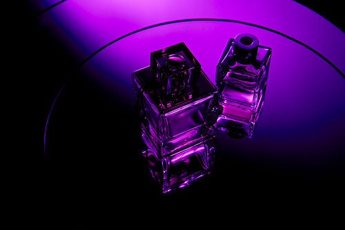 High angle view of purple perfume bottles on round violet mirror surface