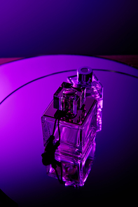 Top view of perfume bottles on round violet mirror dark surface
