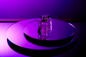 Violet luxury perfume bottles on round mirror surface with reflection isolated on purple