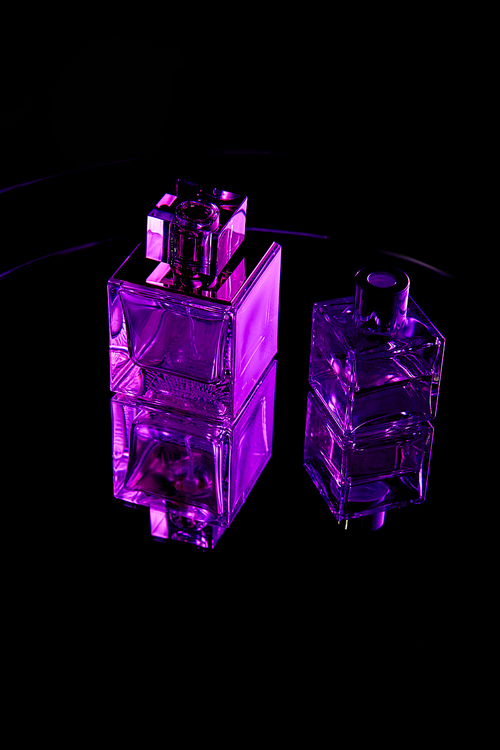 Purple perfume bottles on mirror dark surface isolated on black