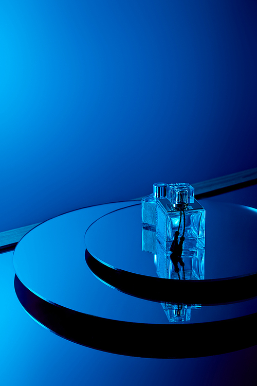 Blue perfume bottles on round mirror surface