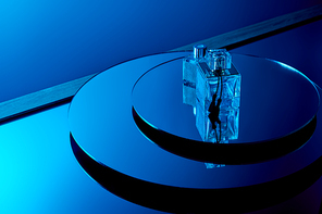 Blue aromatic perfume bottles on round mirror surface