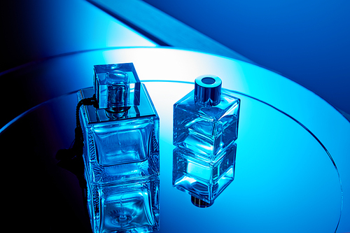 Blue perfume bottles with reflection on round mirror surface