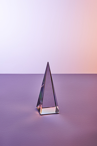 crystal transparent pyramid with light reflection on violet and purple background
