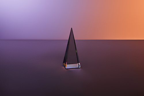 crystal transparent pyramid with light reflection on dark purple background