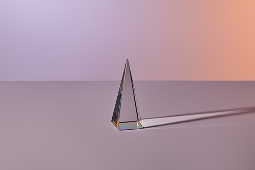 crystal transparent pyramid with light reflection on grey background
