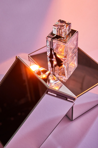 perfume bottle on mirror cubes on pink background with light