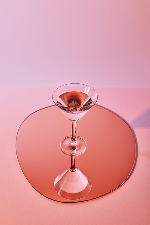 cocktail glass with liquid on mirror with reflection