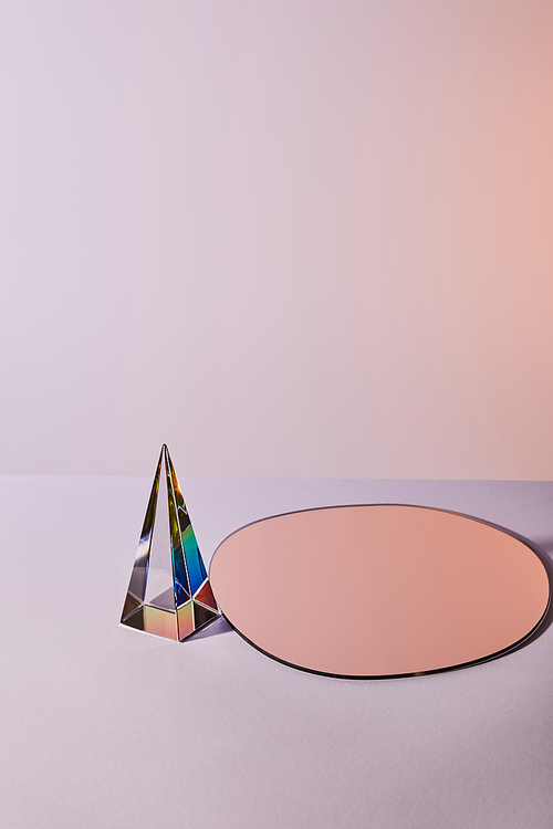 crystal transparent pyramid and round mirror on violet background