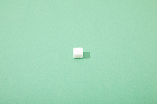 lump sugar cube on green background with copy space