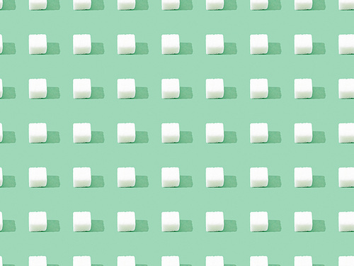 top view of lump sugar on green, seamless background pattern