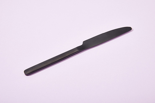 metal shiny black knife on violet background