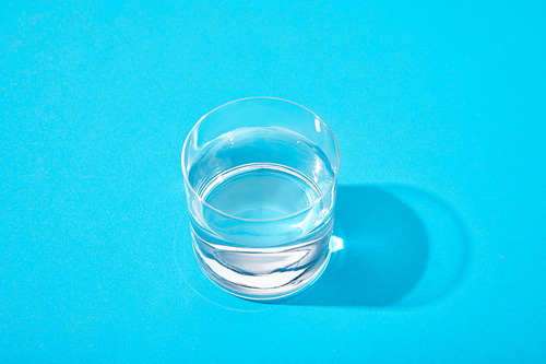 glass of fresh water on blue background